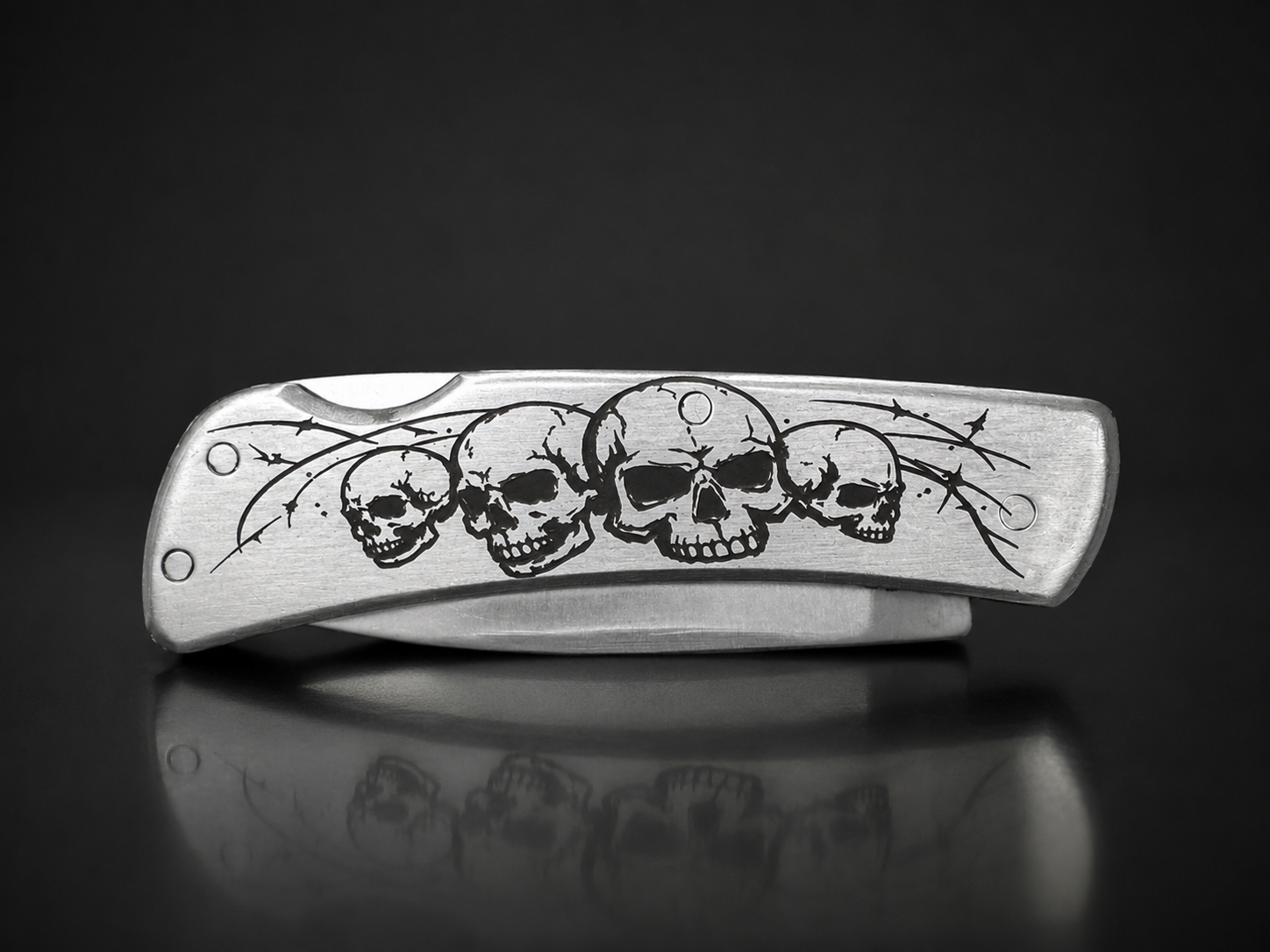 Folding knife with custom skull and barbed wire handle engraving